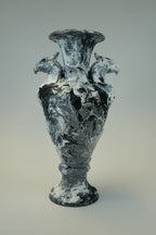 A sculptural vase or vessel made from swirling black, white, and gray materials, photographed against a plain light gray background.