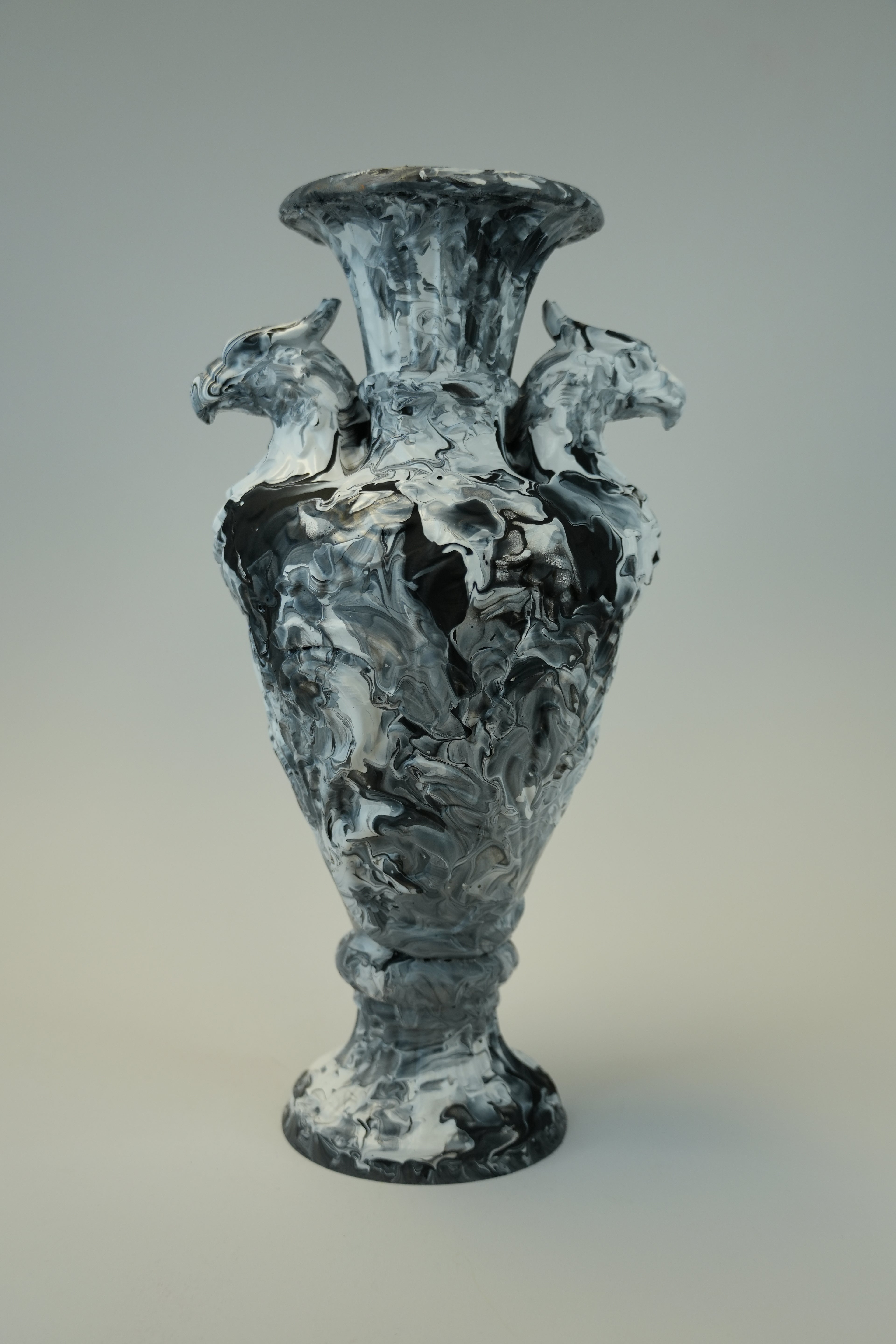 A sculptural vase or vessel made from swirling black, white, and gray materials, photographed against a plain light gray background.