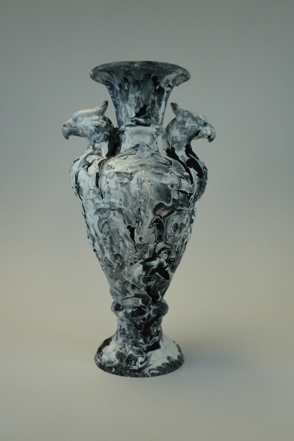 A sculptural black and white textured vase with two horse figures on the shoulders, set against a neutral gray background.