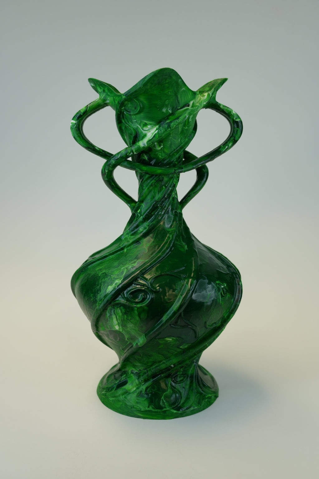 A sculptural green vase with a bulbous base, twisted spiral forms, and a flared organic top, photographed on a light gray studio background.