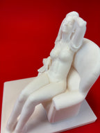 White marble sculpture of a reclining figure on a red background
