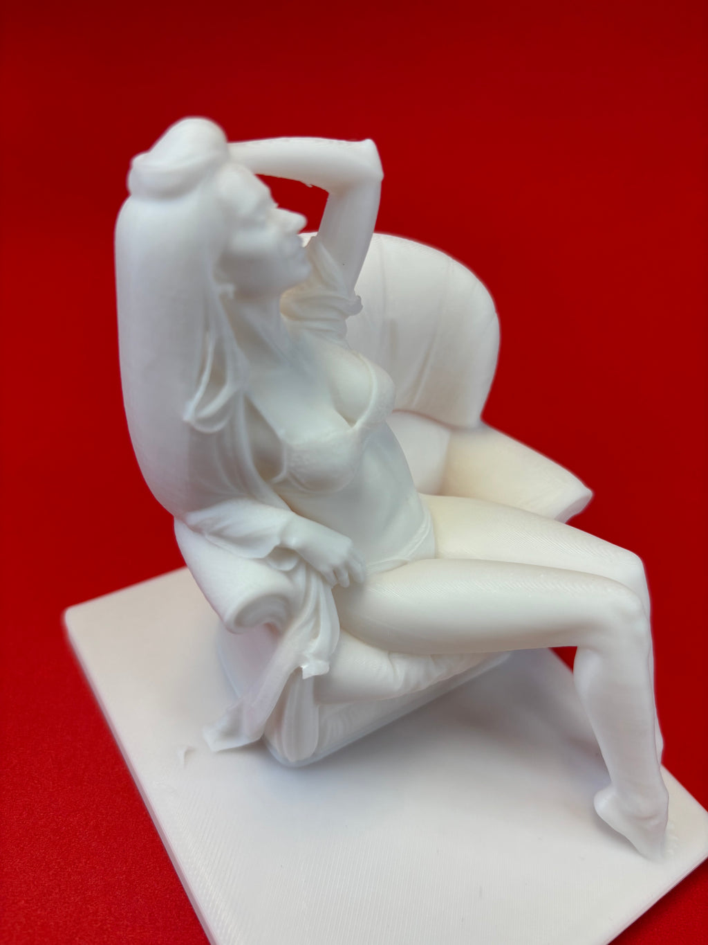 White sculpture of a reclining figure on a red background