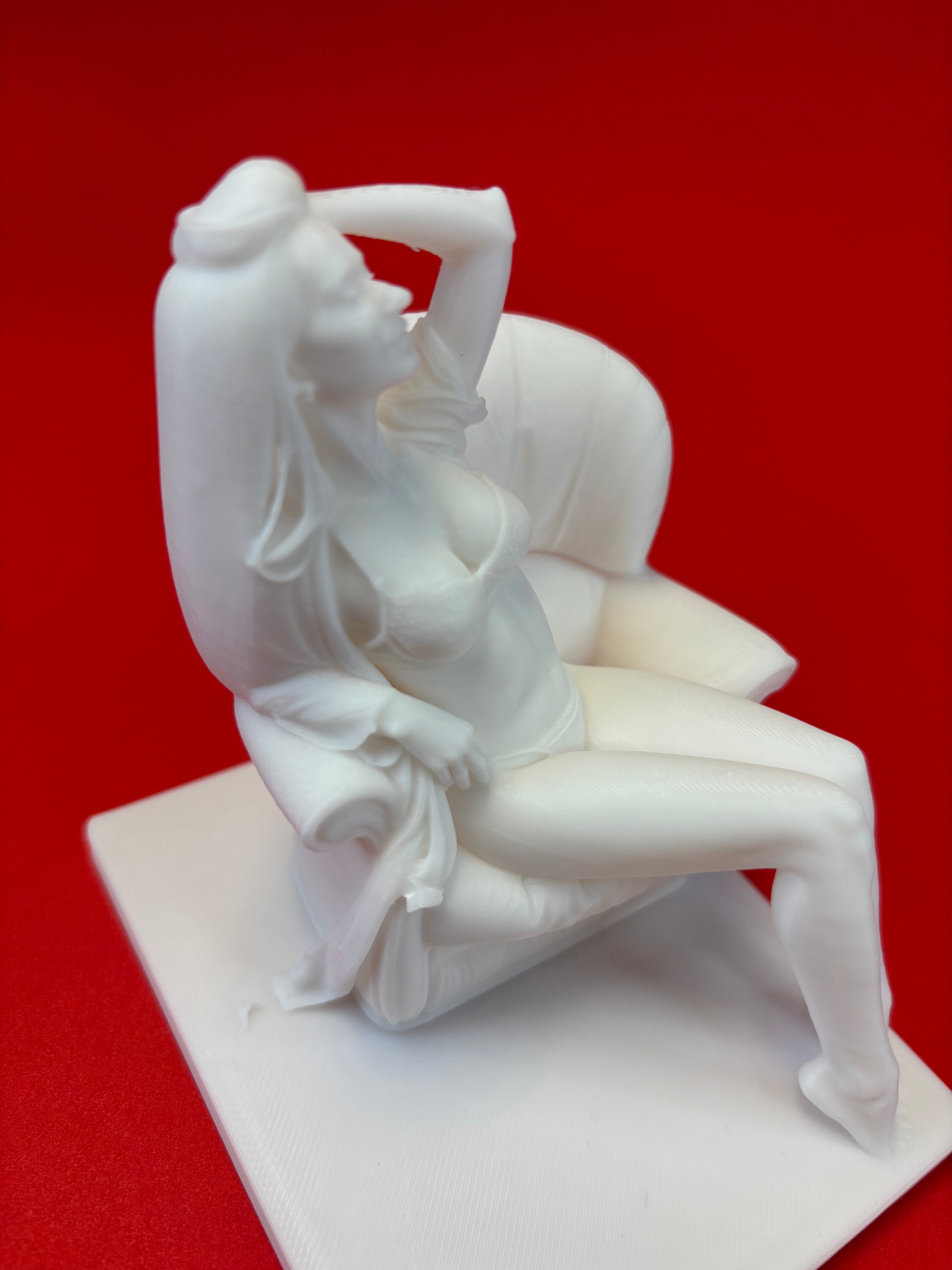 White sculpture of a reclining figure on a red background