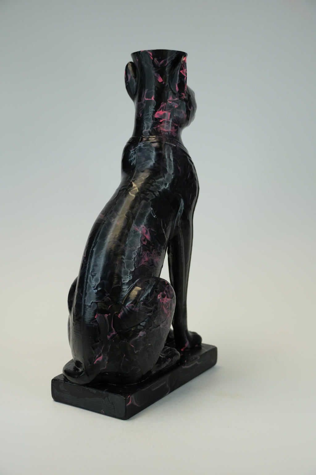 A glossy black cat figurine with pink and gold marbled accents, shown from the back on a light gray background.