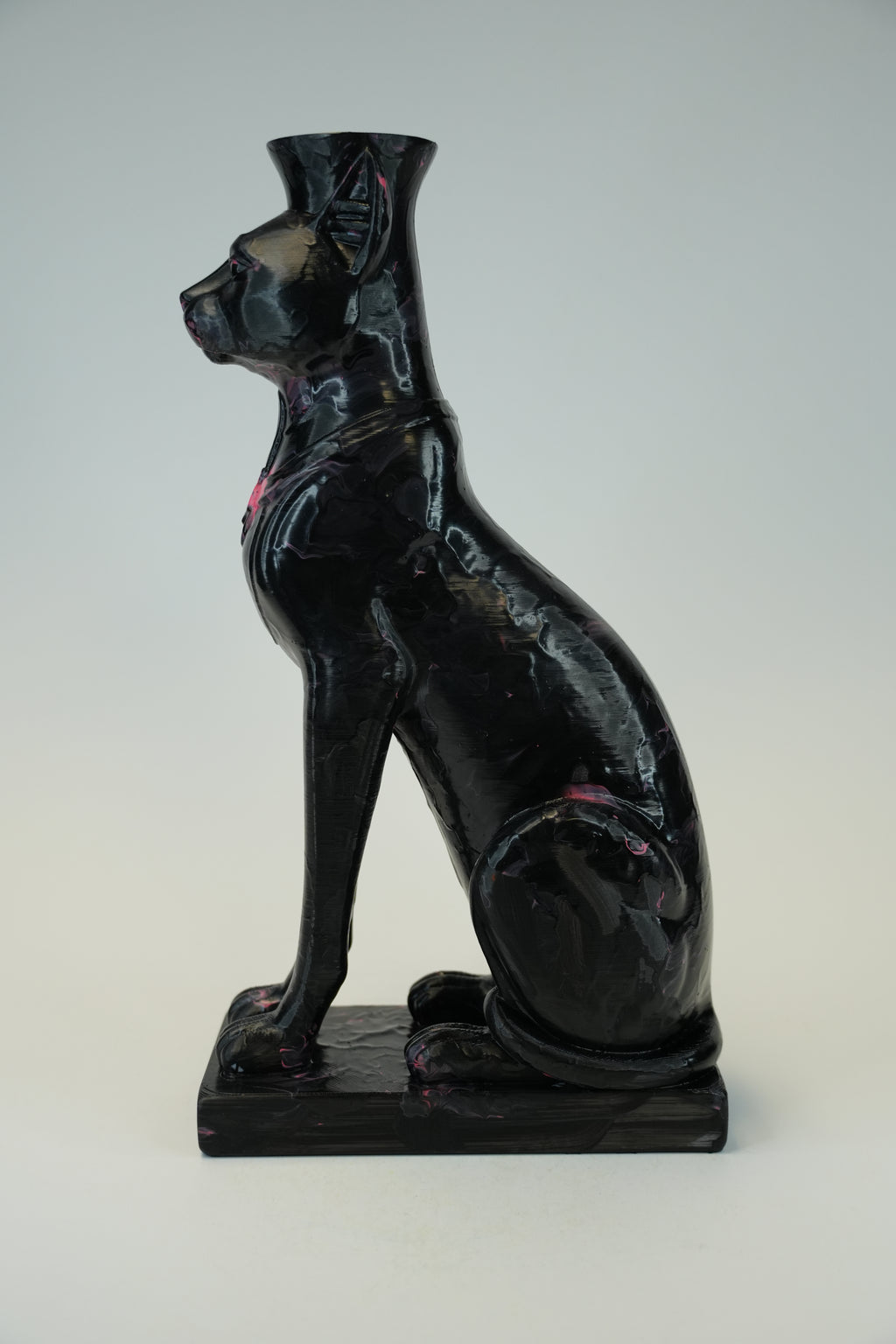 A glossy black cat-shaped vase or sculpture with a flared top, shown in profile on a rectangular base against a light gray studio background.