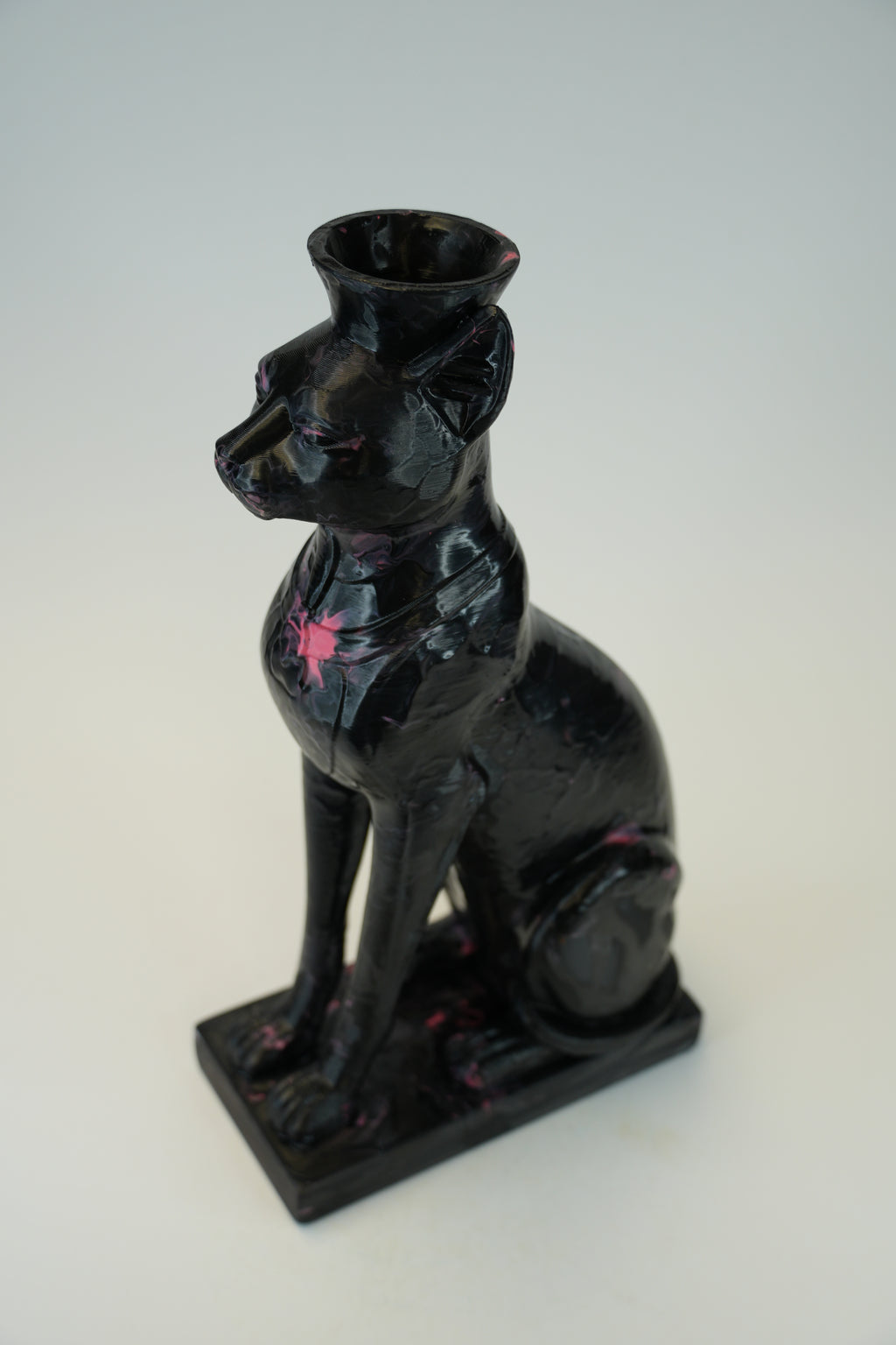 A glossy black cat-shaped candle holder or vase with small pink painted accents, shown on a plain light background.