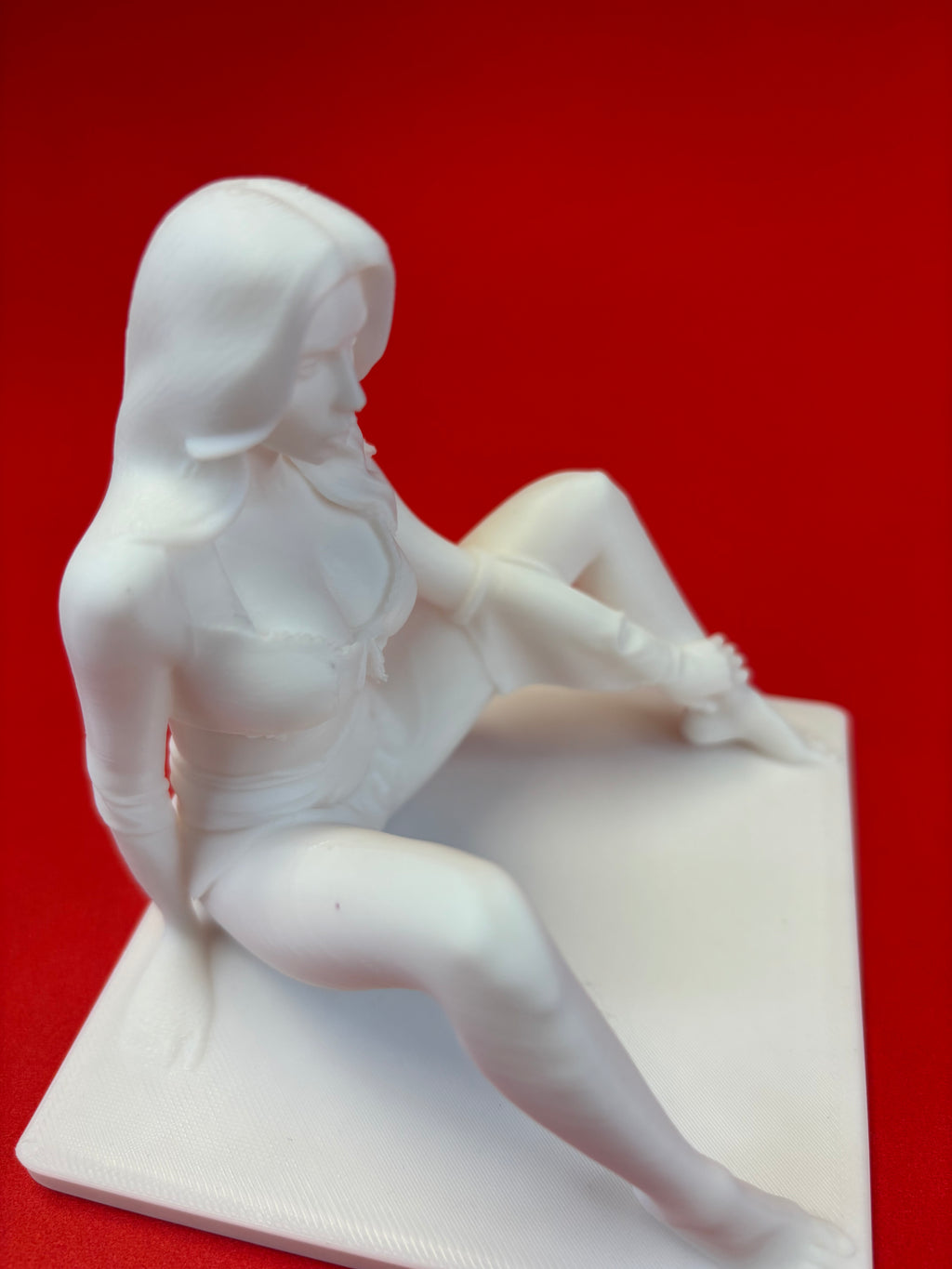 White sculpture of a seated figure on a red background