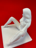 White sculpture of a reclining woman on a red background