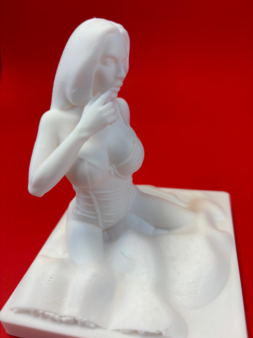 White sculpture of a figure on a red background