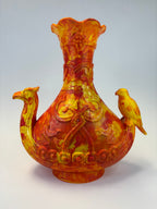 A sculptural ceramic vase with a bulbous body, flared rim, and two bird-shaped handles, painted in a marbled mix of yellow, orange, and red glaze against a plain light background.