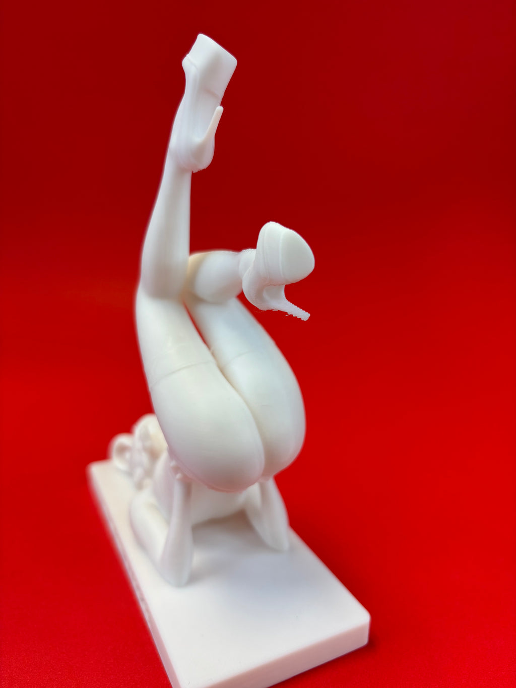 White sculpture of a person in a yoga pose on a red background