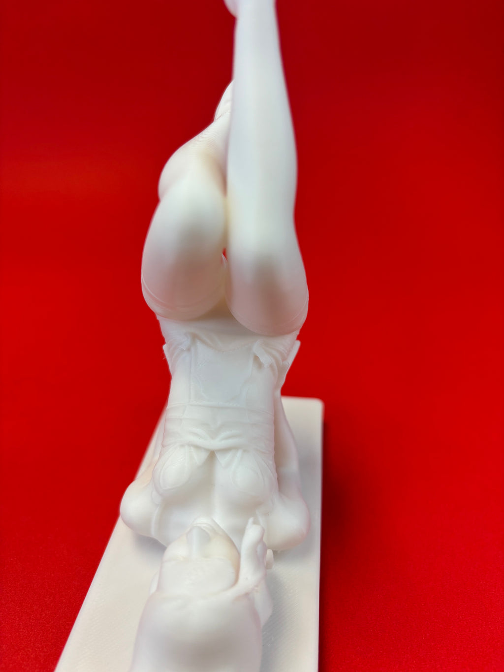 White sculpture of a figure against a red background