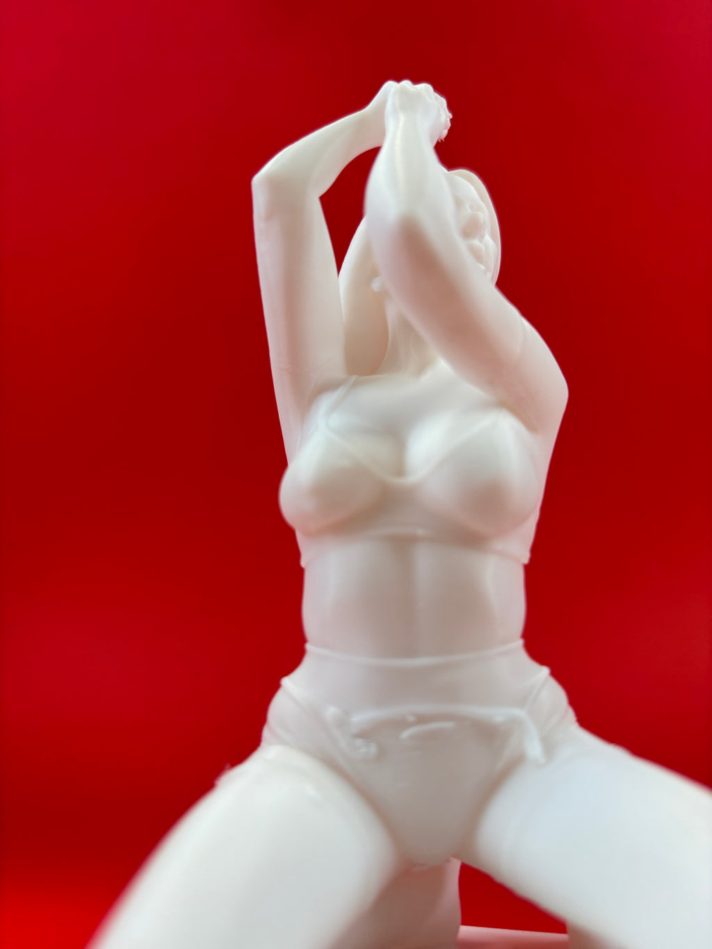 White ceramic figurine of a woman against a red background