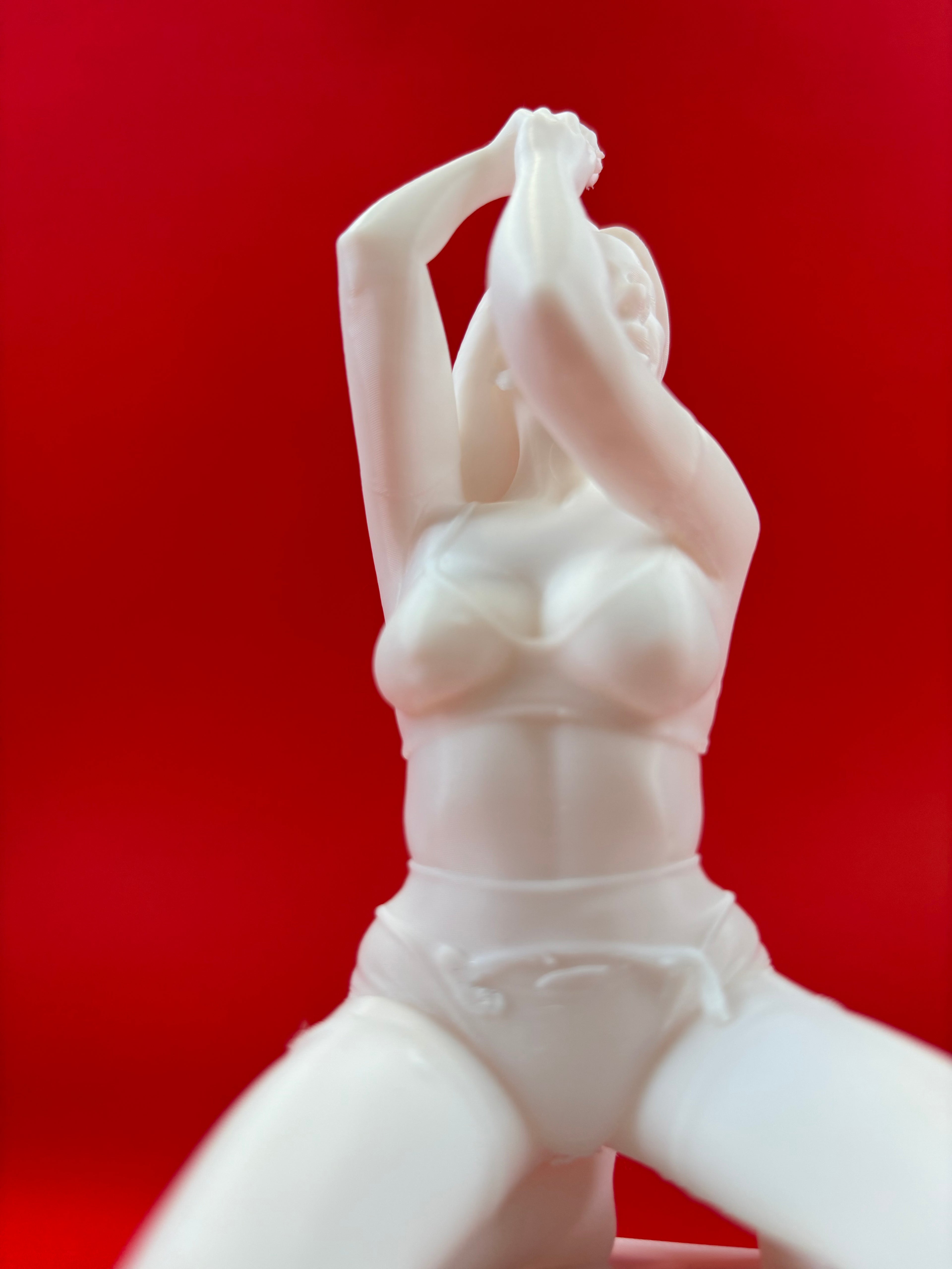 White ceramic figurine of a woman against a red background