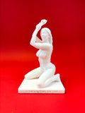 White sculpture of a reclining figure on a red background