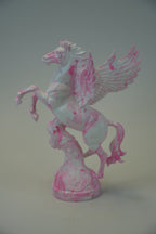 A pink and white marbled Pegasus figurine standing on a matching base, photographed against a neutral gray studio background.