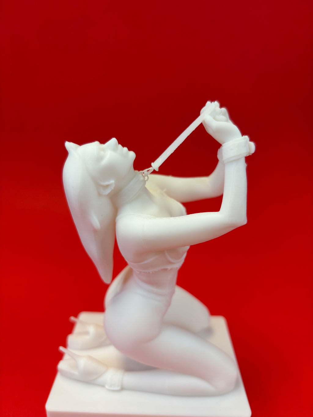 White sculpture of a woman in a dynamic pose against a red background