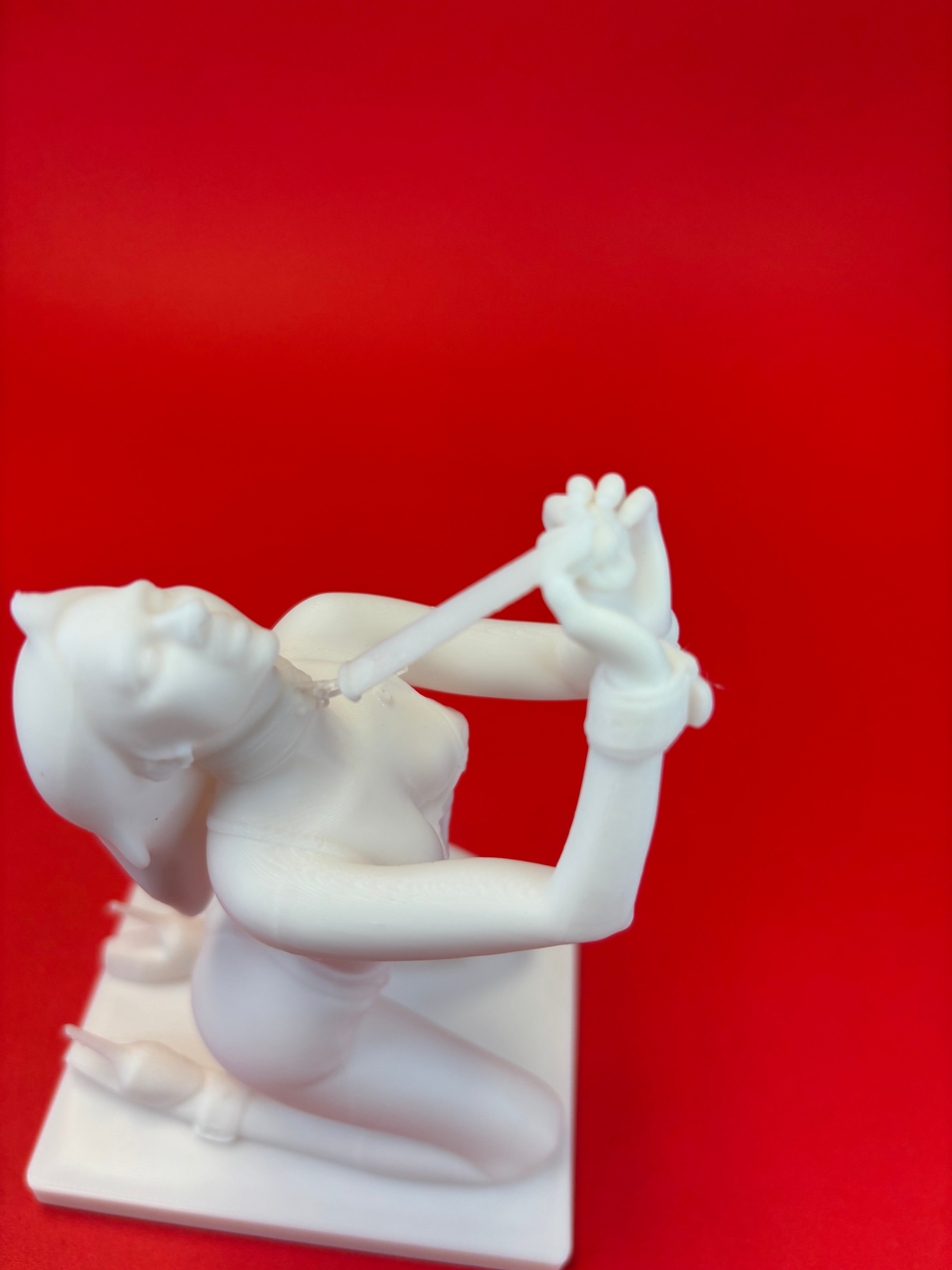 White sculpture of a person in a bond pose against a red background