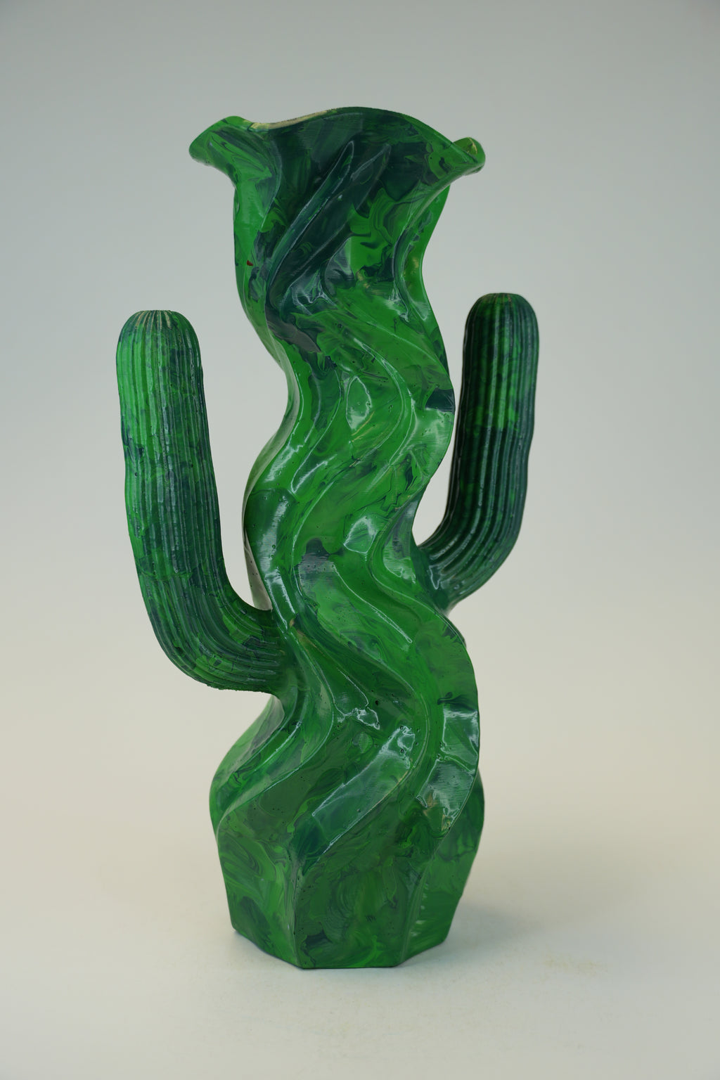 A sculptural green cactus-shaped vase made of polished stone, featuring a wavy, flowing pattern and ribbed arms, set against a neutral light gray background.