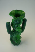 A sculptural green glass vase shaped like a cactus with a flared, flower-like top, photographed on a plain light background.