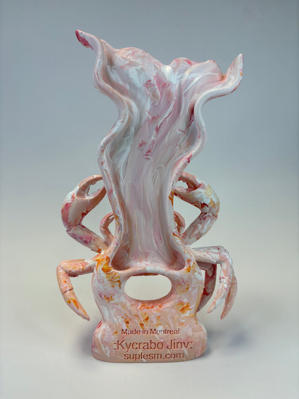 A sculptural decor with a pink, white, and orange marbled design, featuring a stylized crab photographed against a neutral gray background.