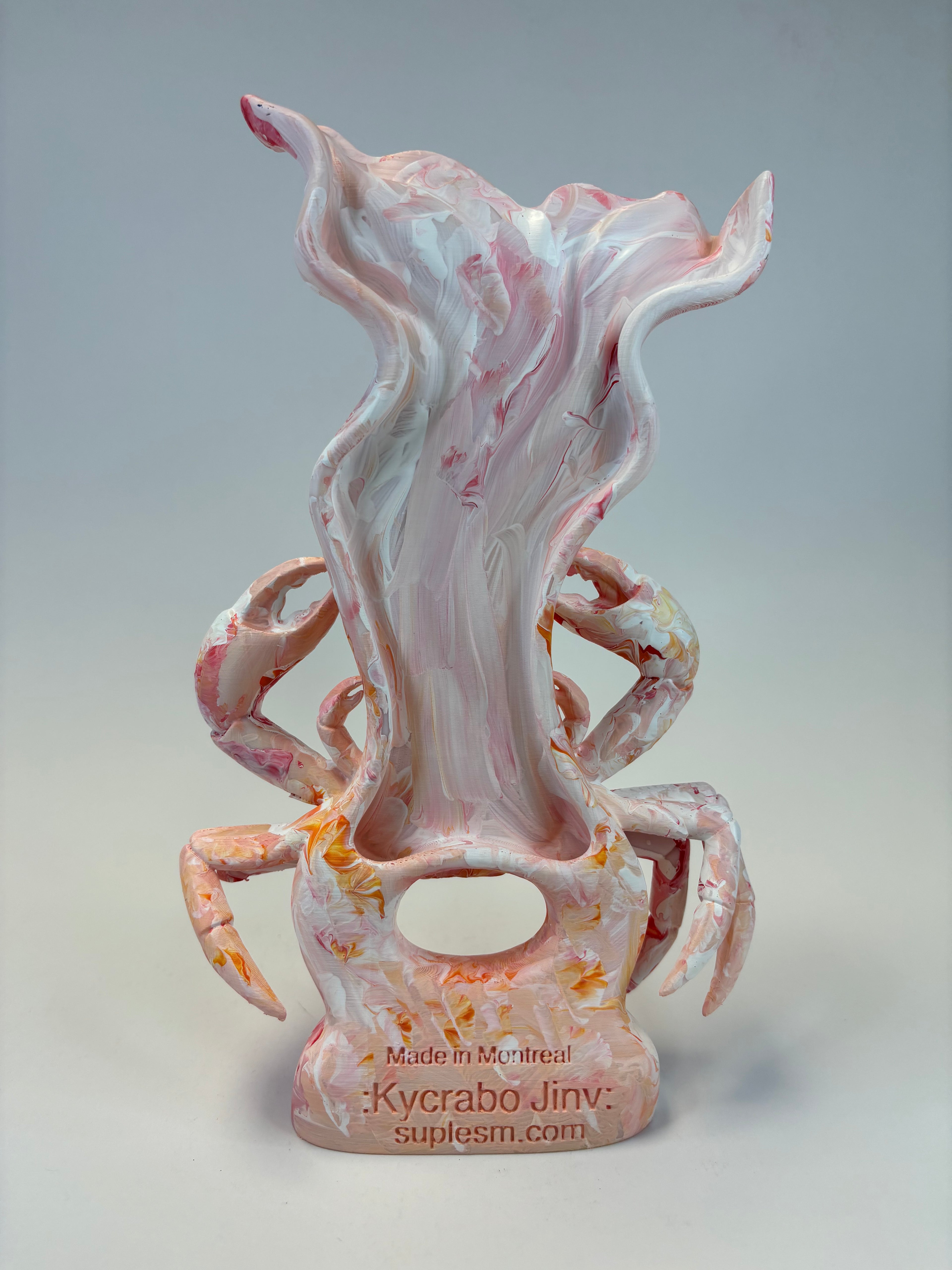 A sculptural decor with a pink, white, and orange marbled design, featuring a stylized crab photographed against a neutral gray background.