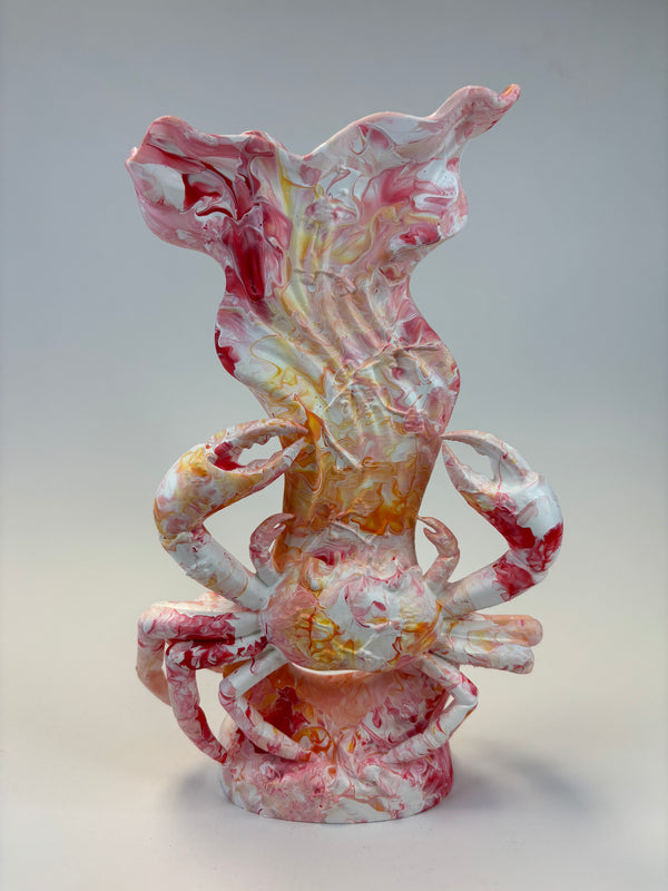 Marbled sculpture of a crab supporting a shell-like form, featuring swirls of pink, white, and orange-yellow on a neutral studio background.