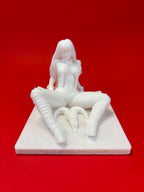 White figurine of a seated woman on a red background