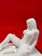 White sculpture of a woman sitting on a red background
