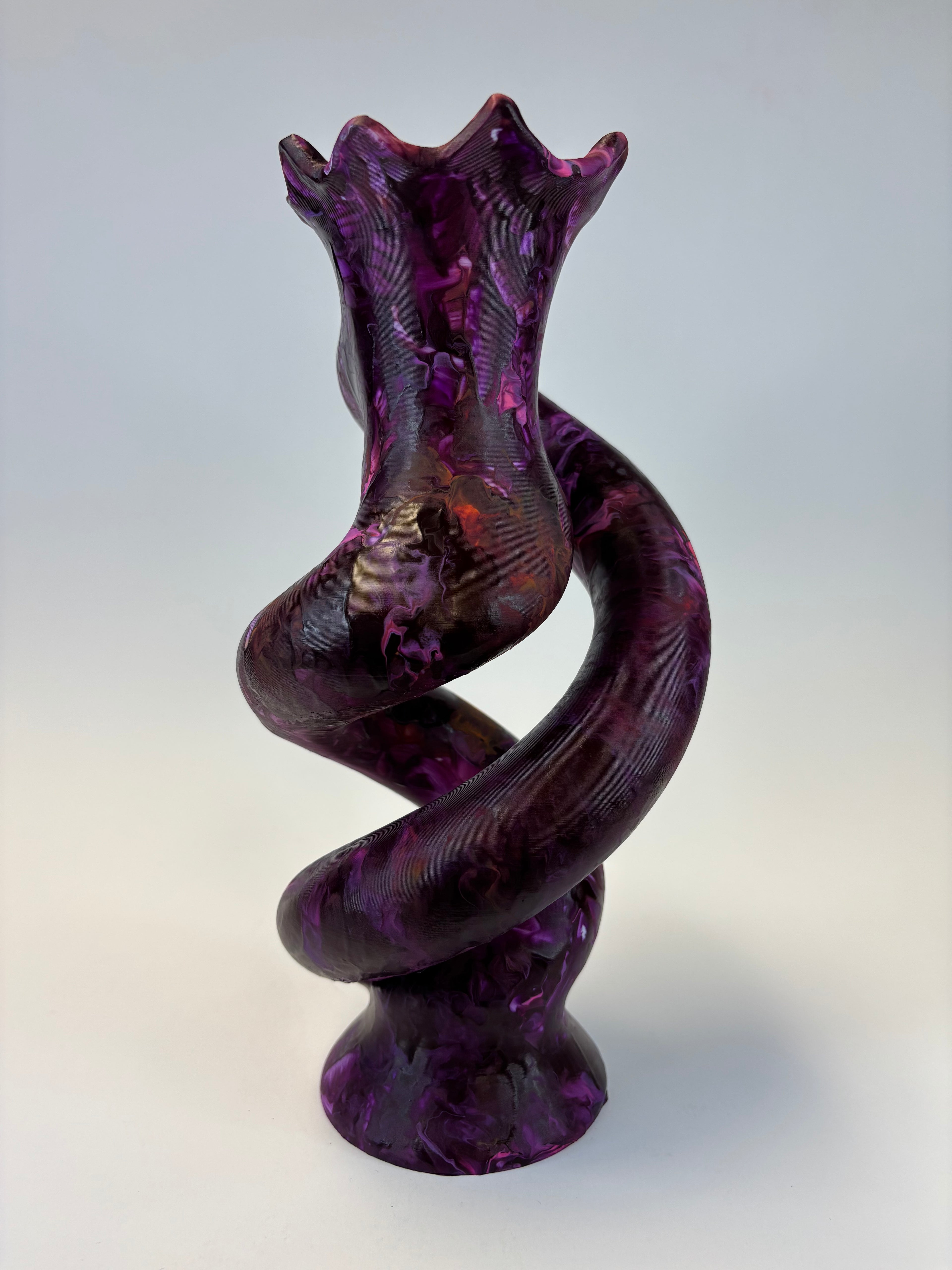 A sculptural spiral object made of glossy, marbled purple glass with darker shading, set against a neutral light gray background.