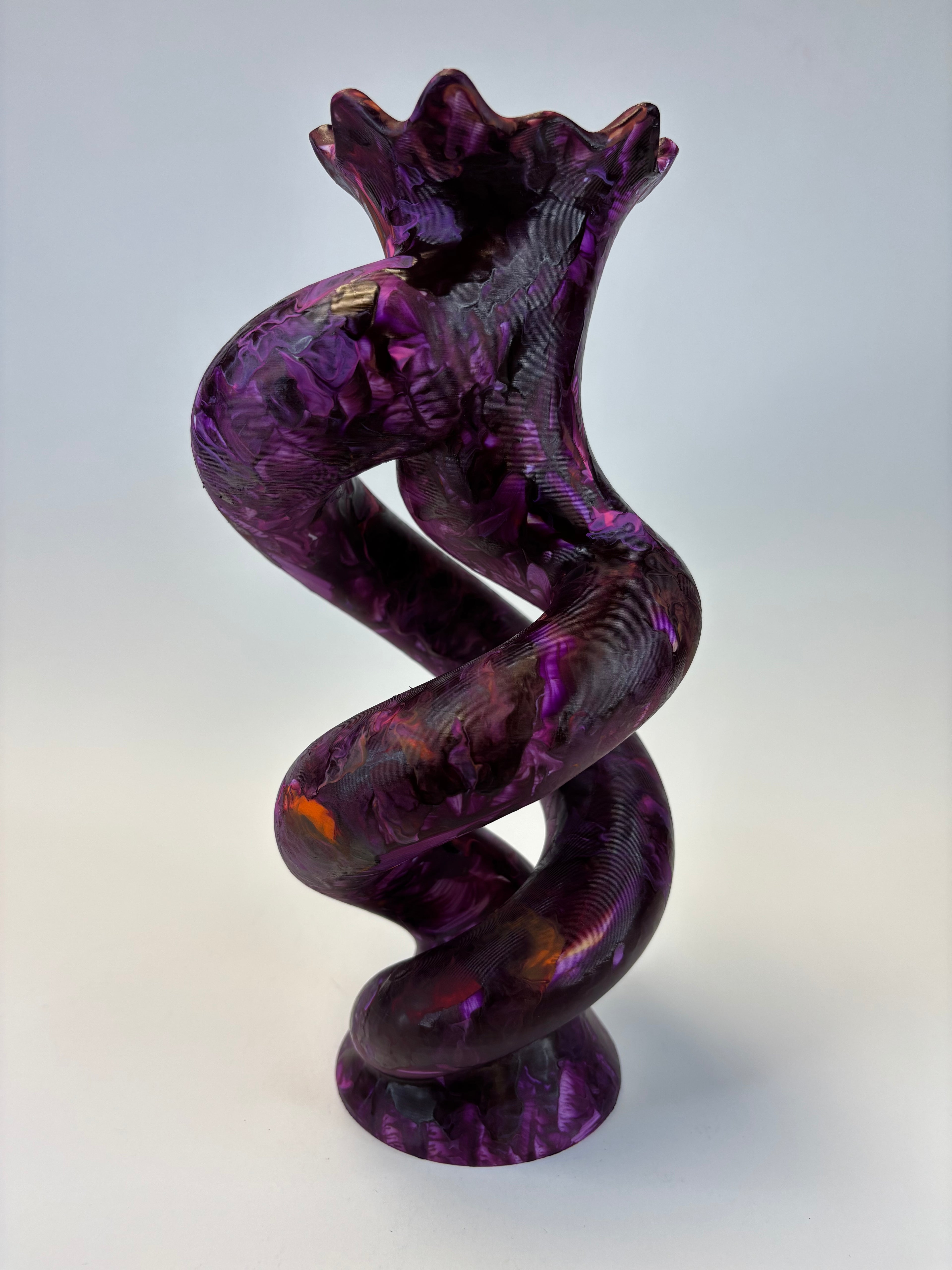 A glossy, twisted sculptural object in deep purple with marbled lighter purple and subtle orange highlights, photographed against a plain light gray background.