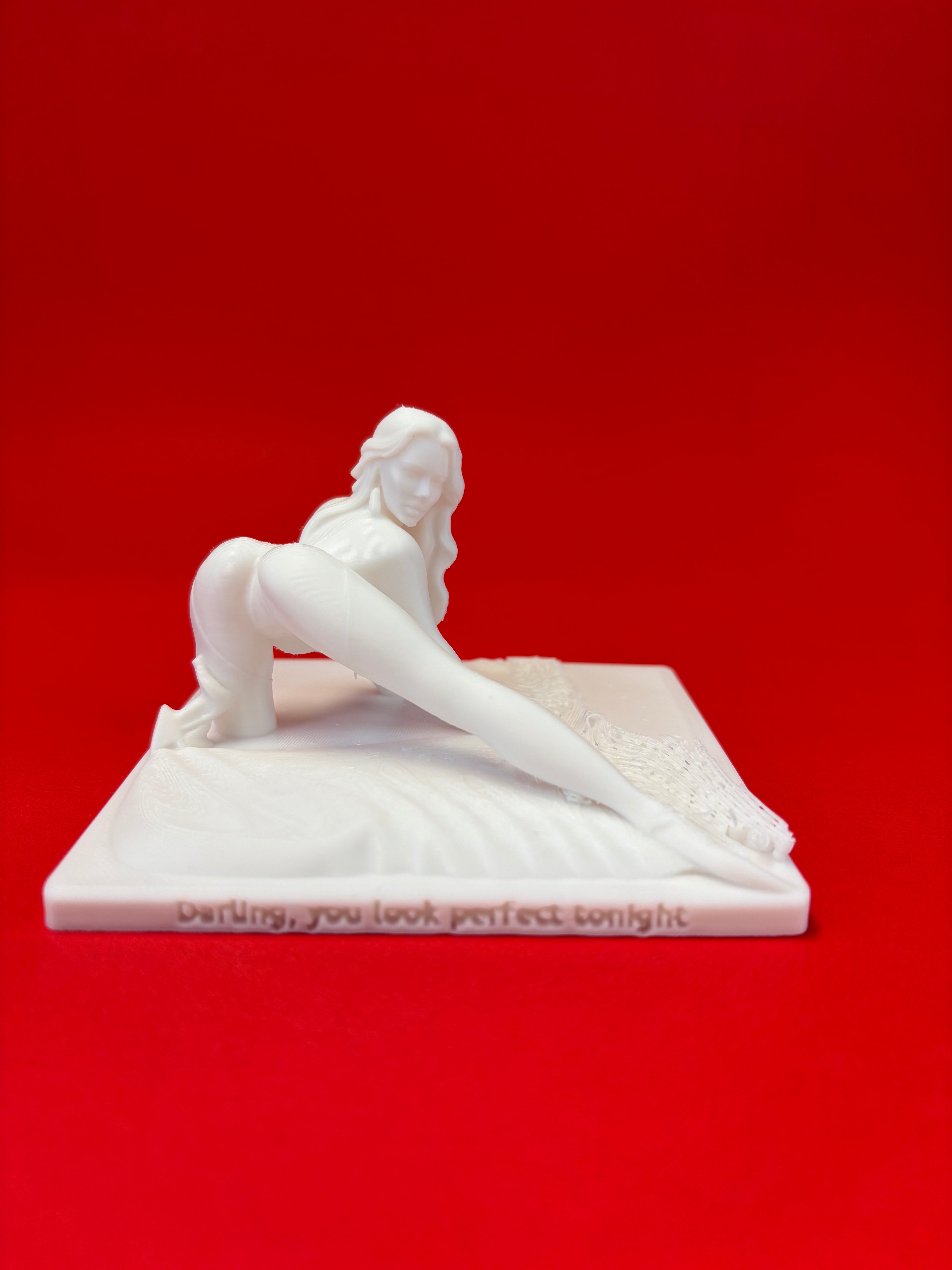 White sculpture of a reclining figure on a red background