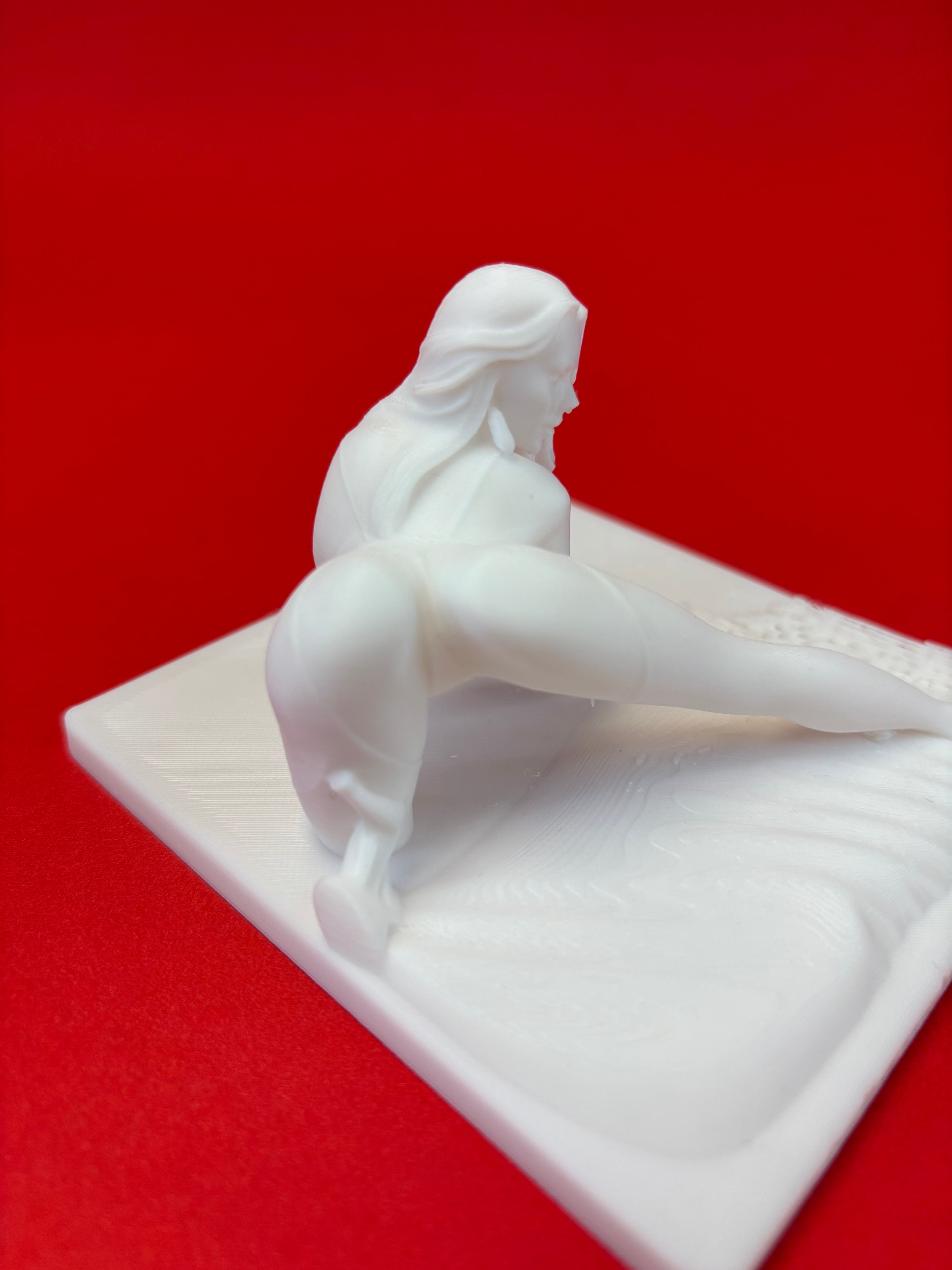 White sculpture of a figure on a red background