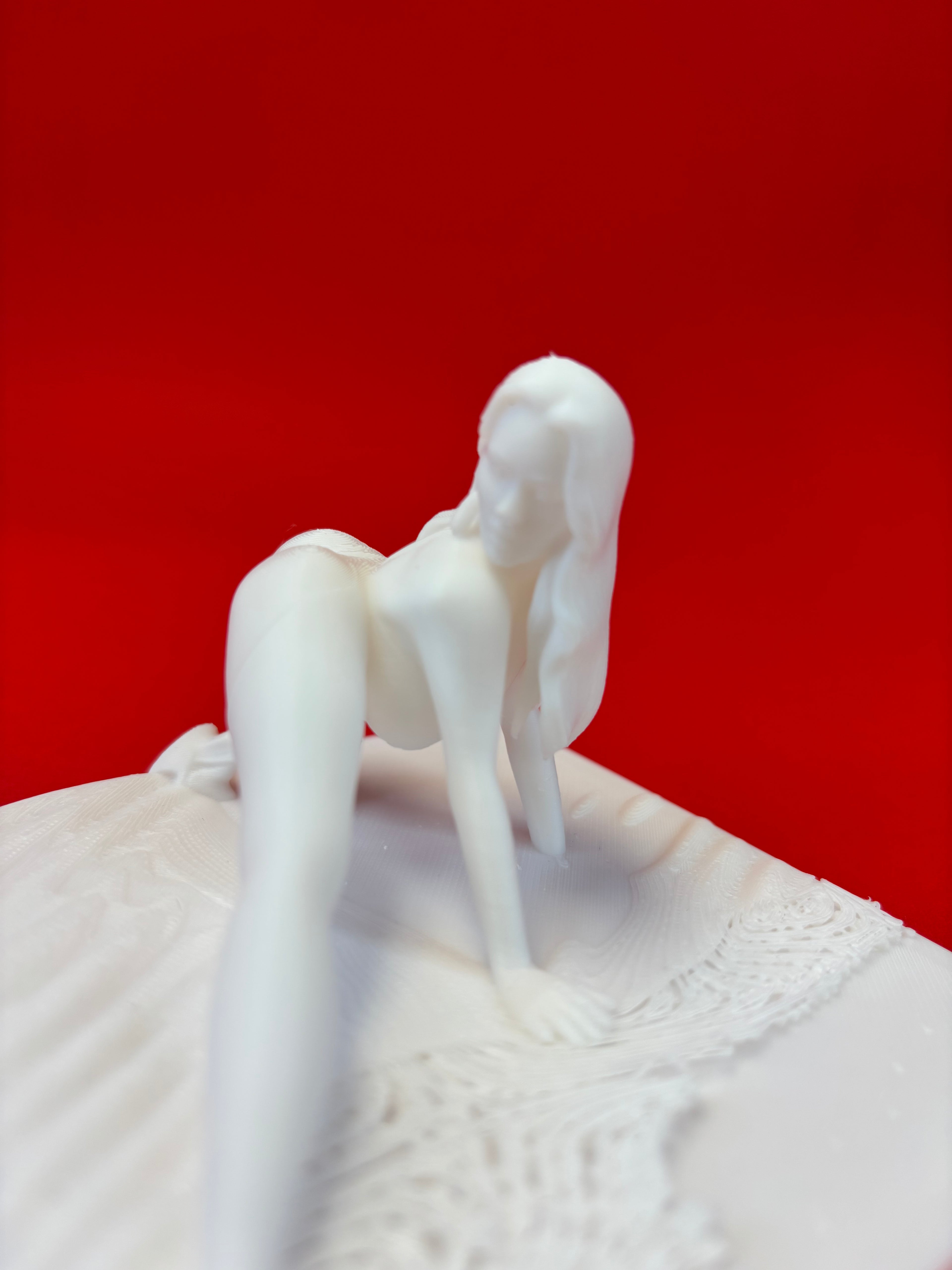 White ceramic figure of a woman on a red background