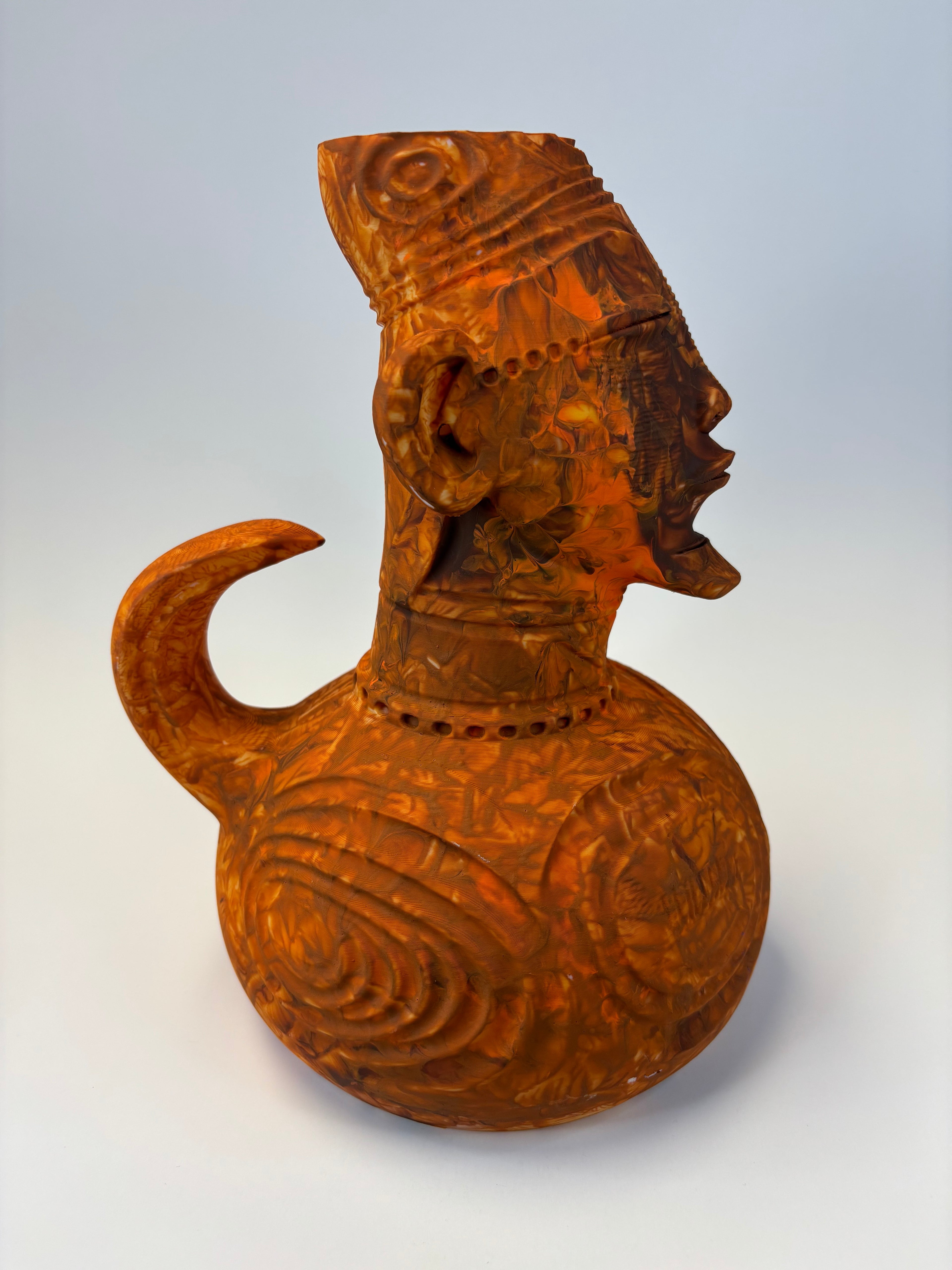 Wooden type clay like sculpture of a face with intricate carvings.