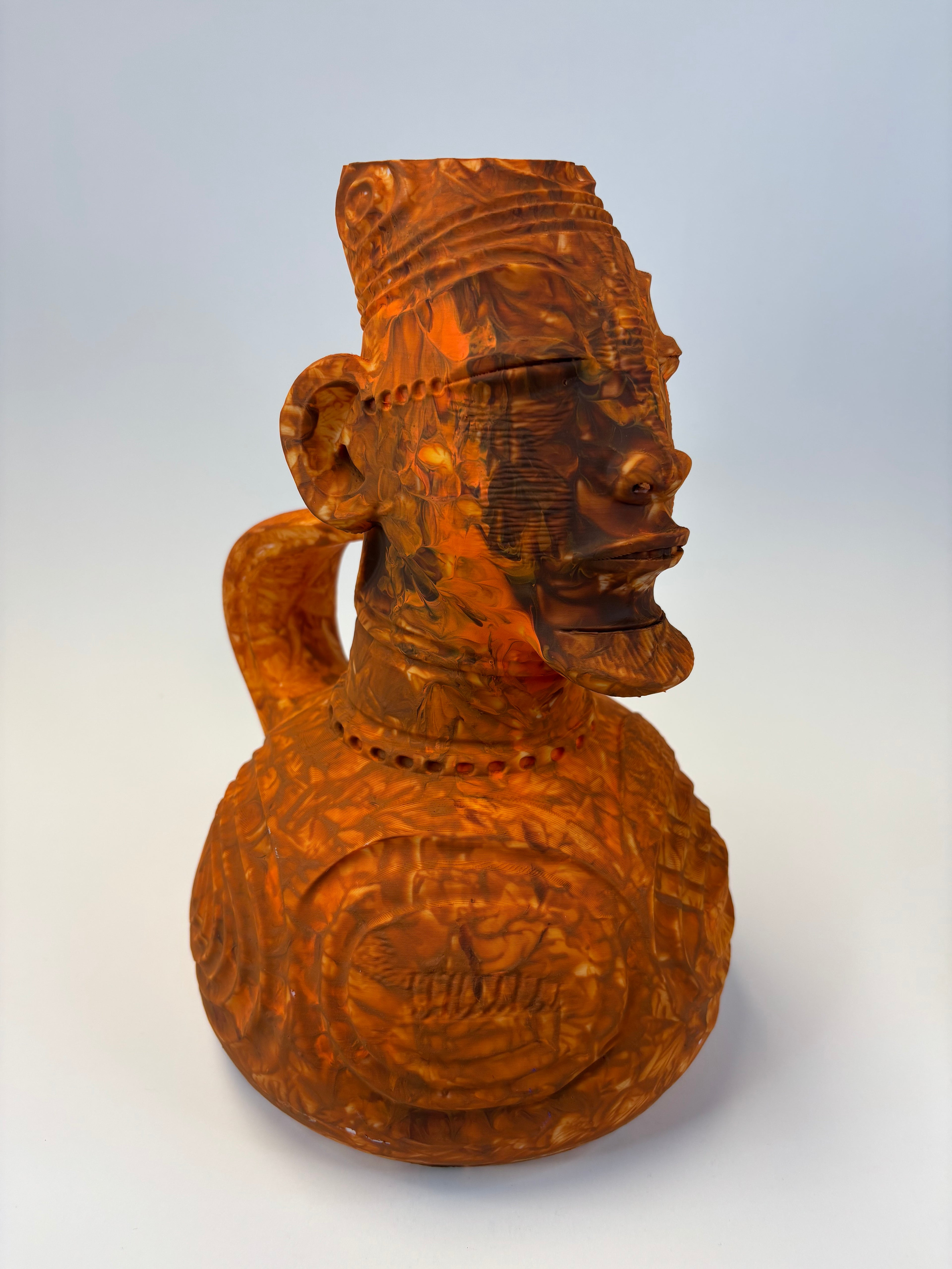 Wooden type clay like sculpture of a face with intricate carvings.