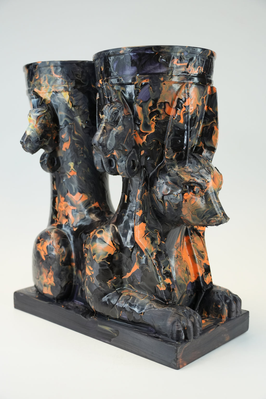A sculptural black and orange marbled ceramic vessel set featuring a seated Anubis jackal motif on a rectangular base, photographed against a light gray studio background.