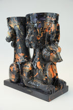 A sculptural black and orange marbled ceramic vessel set featuring a seated Anubis jackal motif on a rectangular base, photographed against a light gray studio background.
