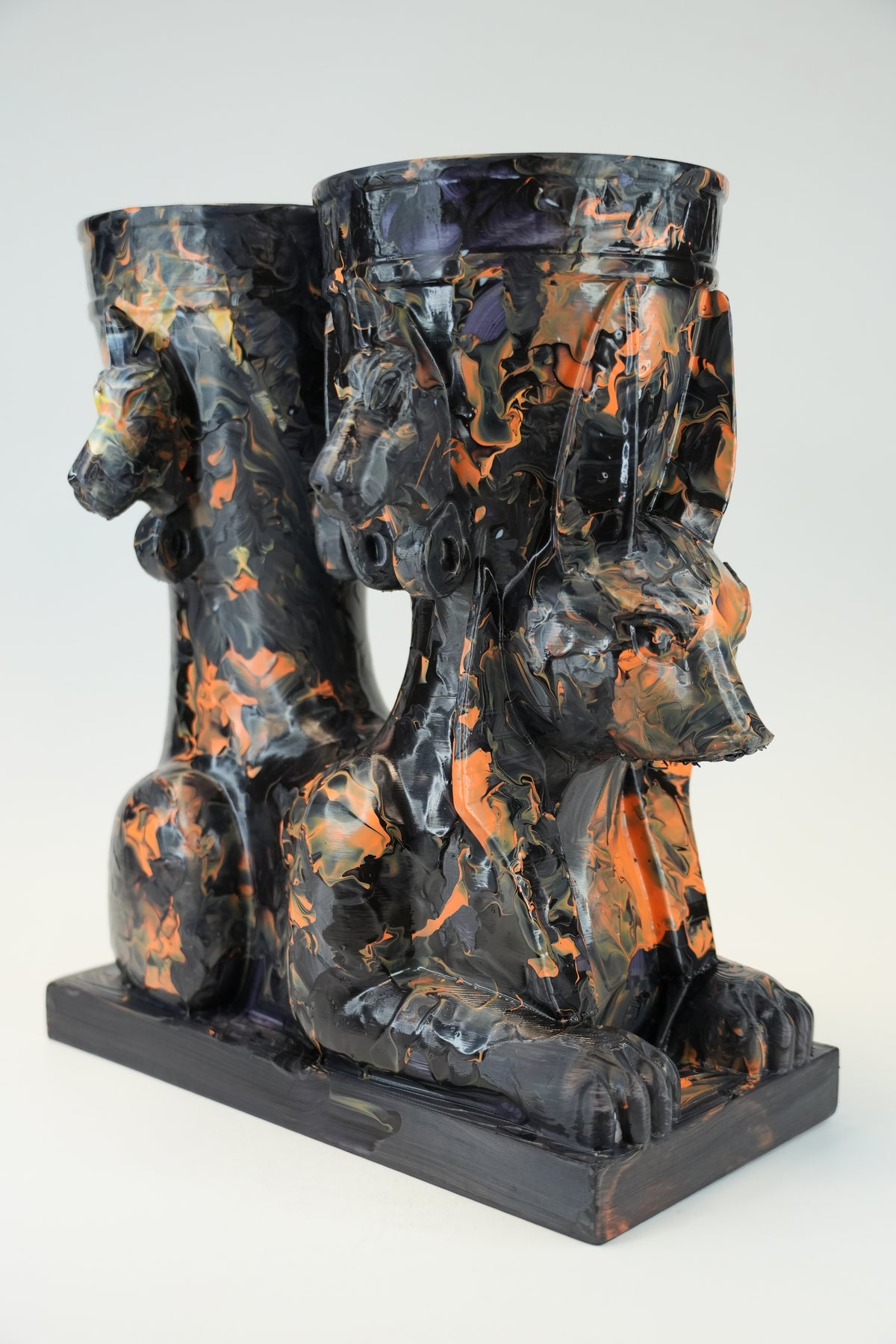 A sculptural black and orange marbled ceramic vessel set featuring a seated Anubis jackal motif on a rectangular base, photographed against a light gray studio background.