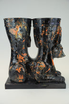 A sculptural black and orange marbled ceramic vessel set featuring a seated Anubis jackal motif on a rectangular base, photographed against a light gray studio background.