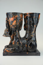 A sculptural black and orange marbled ceramic vessel set featuring a seated Anubis jackal motif on a rectangular base, photographed against a light gray studio background.