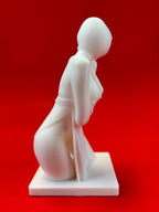 White sculpture of a kneeling figure on a red background
