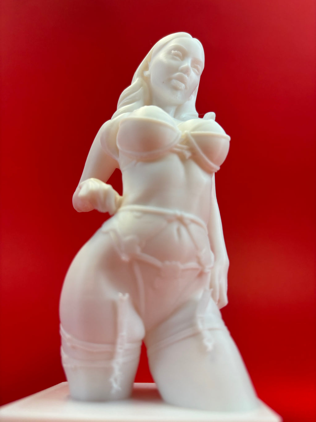 White ceramic sculpture of a figure on a red background