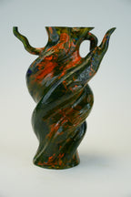 A sculptural twisted vase with a glossy marbled finish in dark green, black, and orange, set against a plain light gray background.