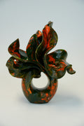 An abstract sculptural vase with a glossy marbled pattern of deep green and burnt orange, photographed on a seamless light gray background.