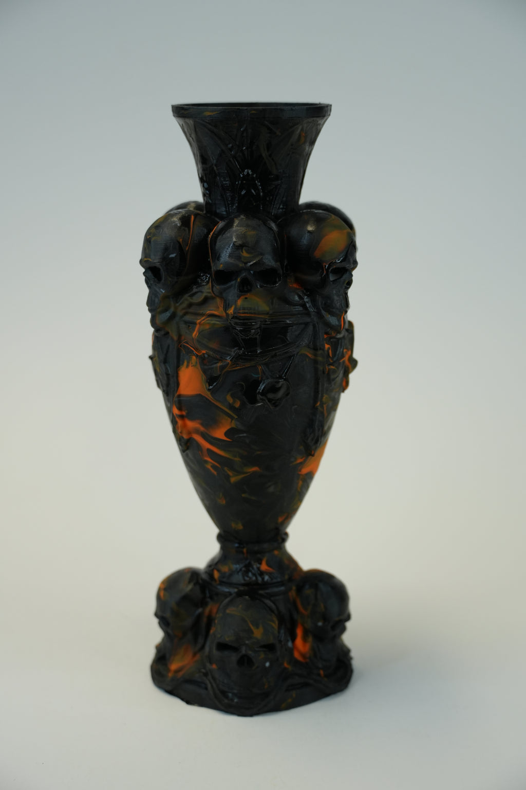 A vintage decorative glass vase with a dark black and amber-orange marbled pattern, photographed against a plain light gray background.