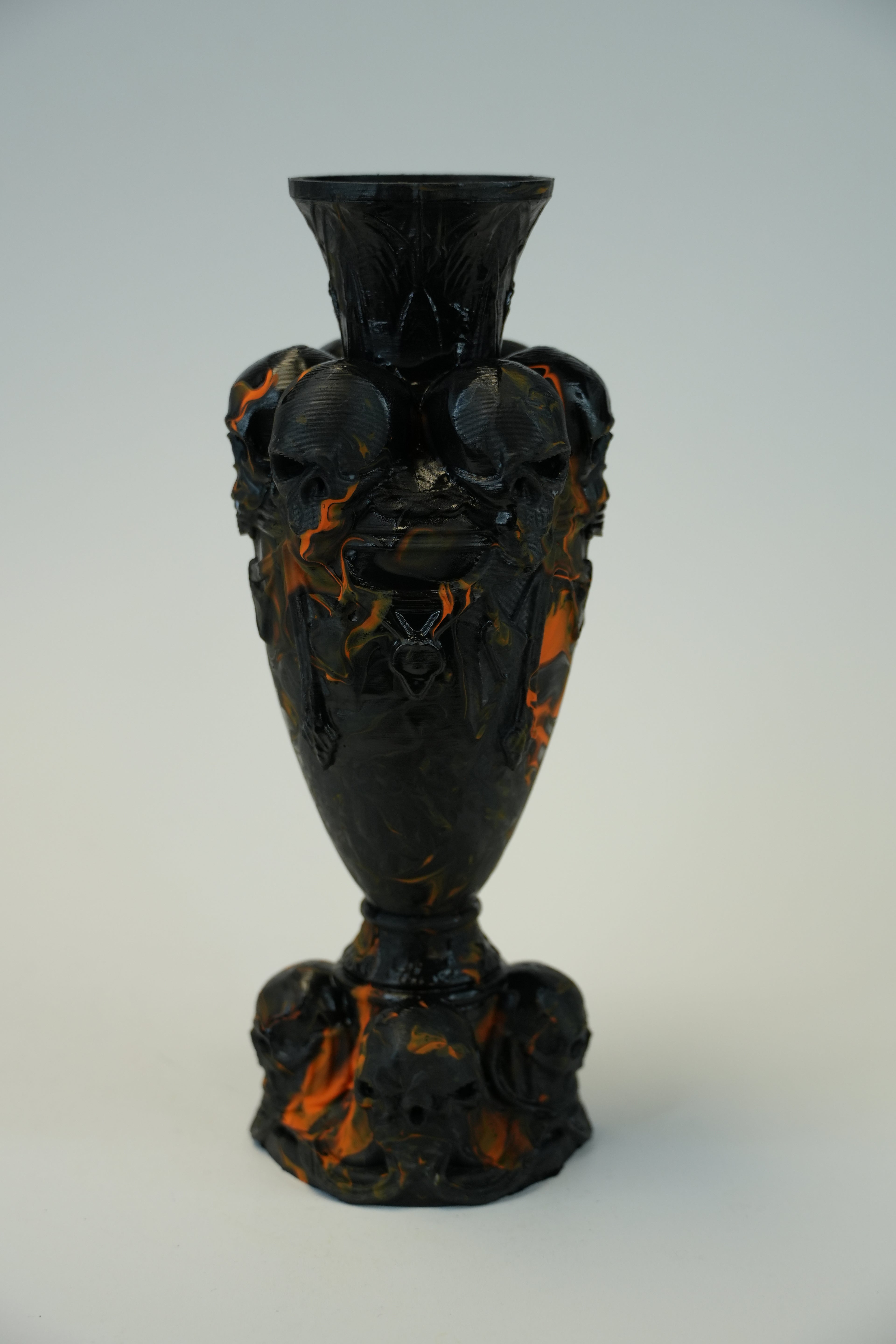 A dark glossy decorative object with a bulb-shaped center, flared rim, and sculpted ends, shown against a plain light background.