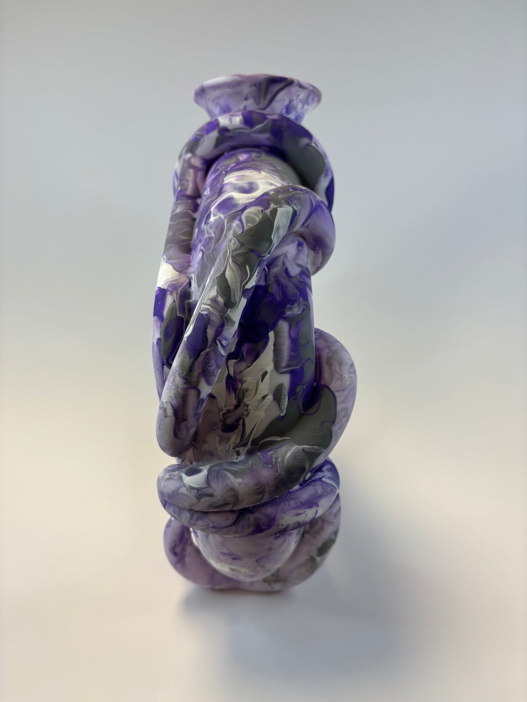 Purple and clear twisted vase on a light gray background