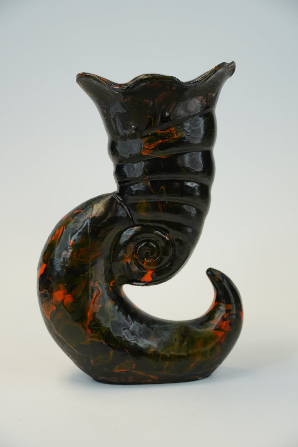 A sculptural wall-mounted cat figurine in glossy black with orange marbled accents, shown against a plain light background.