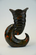 A sculptural wall-mounted cat figurine in glossy black with orange marbled accents, shown against a plain light background.